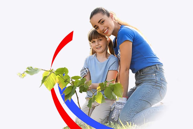 A woman and a small child planting a sapling while volunteering